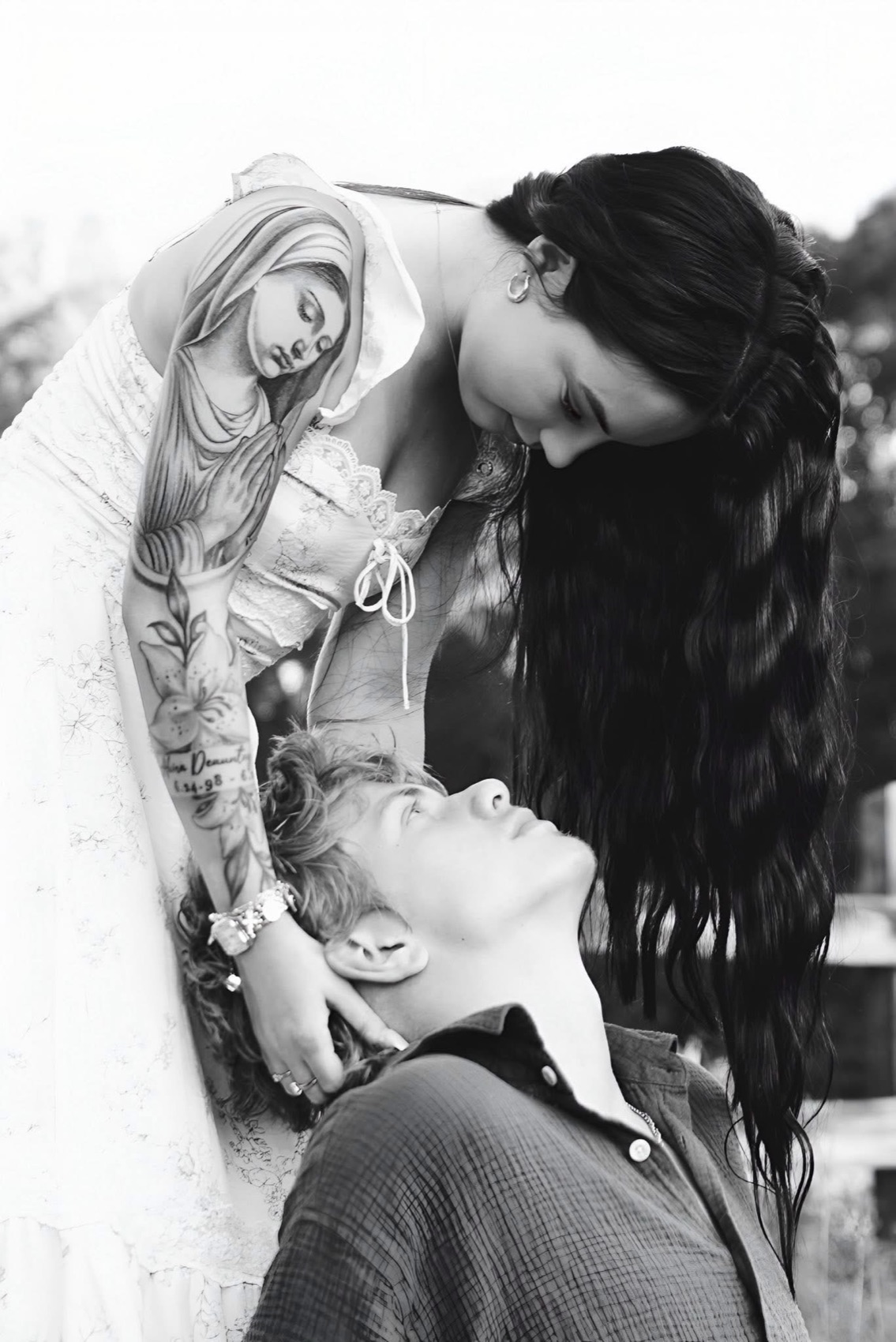 Black and white photograph of a woman leaning down over her partner, cradling the back of his head